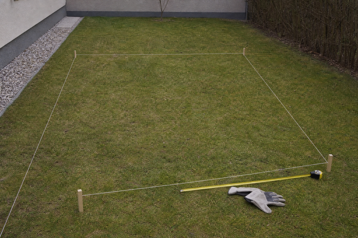 Mit Schnur und Holzpflöcken abgestecktes Rechteck auf einer Rasenfläche – Symbolbild zur Größenwahl